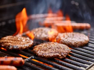 Poster Im Rahmen Hamburger und Hot Dogs, die auf dem Grill mit Flammen kochen © Joshua Resnick