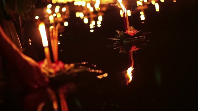 Loi Krathong Festival in Chiangmai, Thailand. Hand releasing floating decorated baskets and candles to pay respect to river goddess. Thai traditional culture on full moon night