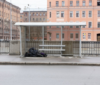 homeless man sleeping at the bus stop