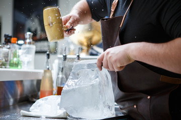 Fototapeta na wymiar Bartender mannually crushed ice with wooden hammer and metal knife.