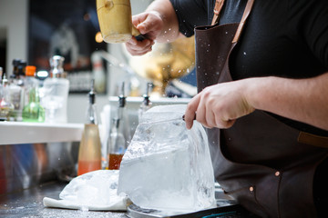 Bartender mannually crushed ice with wooden hammer and metal knife.