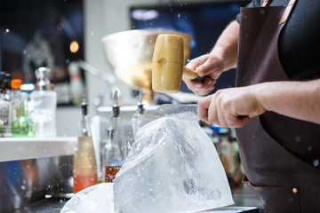 Bartender mannually crushed ice with wooden hammer and metal knife.