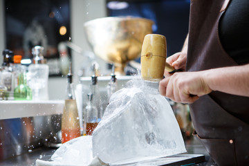 Fototapeta na wymiar Bartender mannually crushed ice with wooden hammer and metal knife.