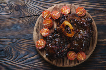 Ossobuco served with baked tomatoes, rustic wooden setting