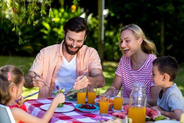 Family enjoying breakfast at table in yard 