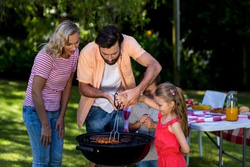 Father with mother teaching children to barbecue food 