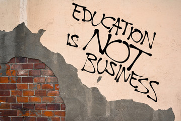 Handwritten graffiti Education Is Not Business sprayed on the wall, anarchist aesthetics