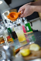 Bartender is straining cocktail in a glass