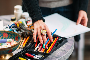 Painter artist chooses a color pencil. Closeup of drawing process in art workplace. Painter...