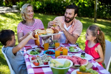 Cheerful family enjoying meal at table in yard 