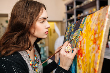 Creative painter paints a colorful picture. Closeup of painting process in art workplace. Painter...