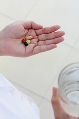 woman hands holding pills and water glass