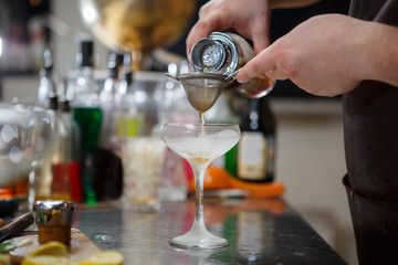 Fototapeta na wymiar Bartender coocks cocktail behind a bar counter