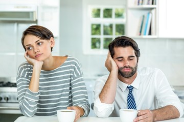 Upset couple with coffee cup sitting at table