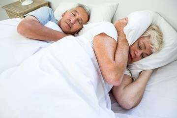 High angle view of senior woman sleeping by snoring man