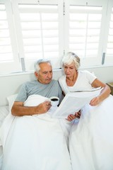 High angle view of senior man and woman reading newspaper