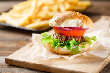 Homemade burger with french fries on wooden table