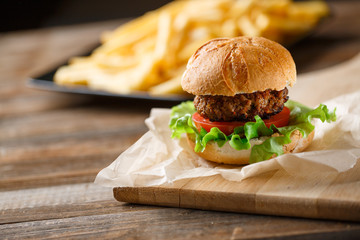 Homemade burger with french fries on wooden table