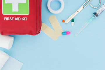 First aid kit with medical equipment, on light blue background with copy-space