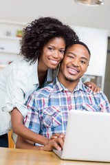 Portrait of young couple using laptop in kitchen