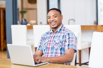 Happy young man using laptop in kitchen