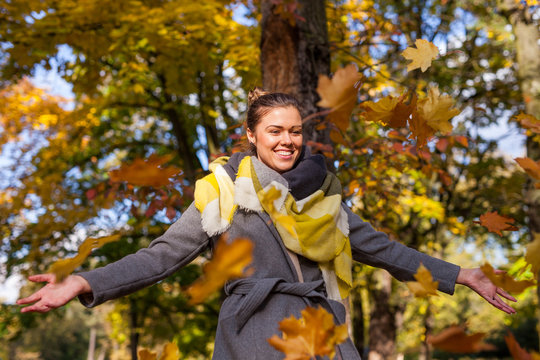 Beautiful girl thowing bunch of colrful leaves. Autumn time.