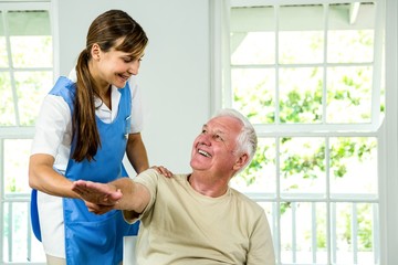 Fototapeta premium Smiling nurse assisting aged man