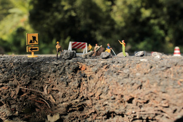 Cracked asphalt road and Roadworks with miniature figurines in a country setting.Soft Focus and Shallow Depth of Field Composition.