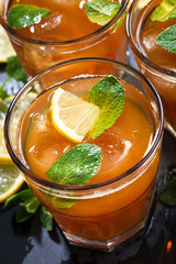 iced tea with mint and lemon in glasses on dark background