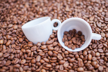 Two coffee mug in pile of coffee beans. Background.