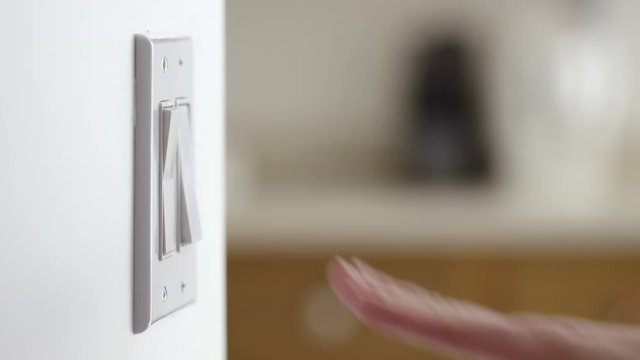 Close up of a hand reaching in and turning light switches on, then off.  Originally recorded in 4K
