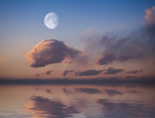 Fototapeta na wymiar Moon with sunset sky reflected in water surface.