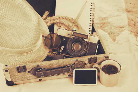 traveling concept. camera, cup of coffee, sunglasses, fedora hat and notebook. sepia vintage style filtered. selective focus