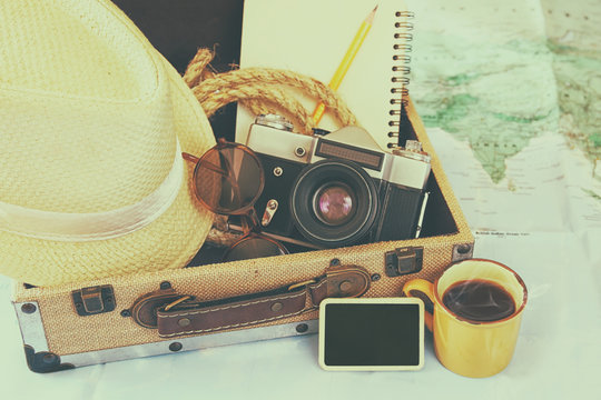 traveling concept. camera, cup of coffee, sunglasses, fedora hat and notebook. vintage filtered. selective focus