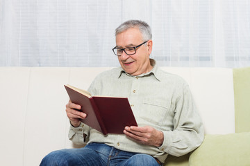 Naklejka premium Senior man enjoys reading book.