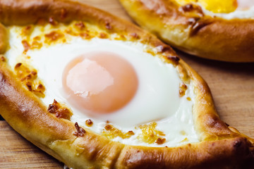 Hachapuri on Adjara. Beautiful open pies khachapuri with egg and onions on wooden background