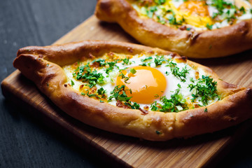 Hachapuri on Adjara. Beautiful open pies khachapuri with egg and onions on wooden background