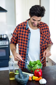 Portrait of man mixing a salad in kitchen