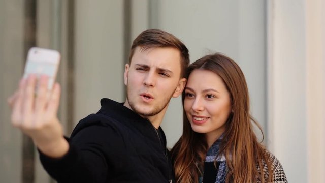 Beautiful attractive smiling woman taking selfies with her handsome boyfriend on her phone.