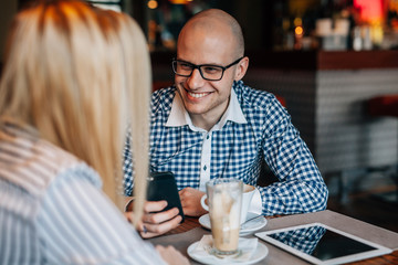 Young boy and girl drinking coffee in the cafe. Tablet pc and mo