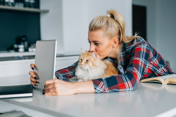 Young girl is taking picture of her and the cat using tablet pc.