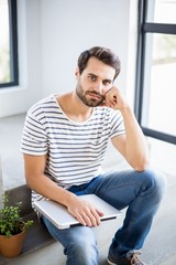 Portrait of thoughtful man sitting on steps with laptop