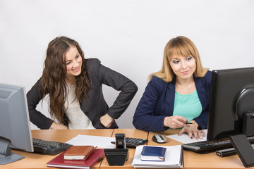 Office worker with feigned indignation looking at the colleague sitting next to the computer...
