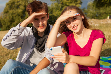 Two friends in a park with mobile phone. Summer time.