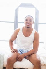 Smiling young man sitting on bed