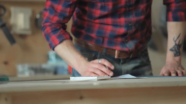 Worker carpenter writes the data on paper