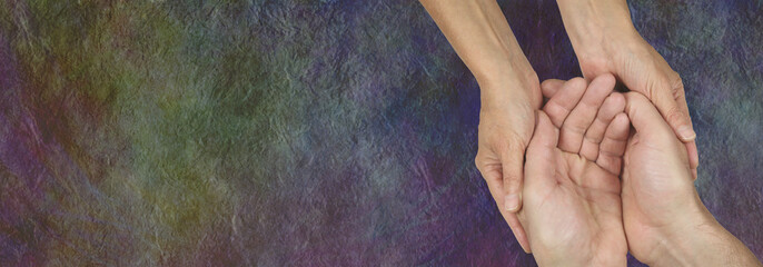 Caring for those in need -  rustic dark stone effect wide background with a womans hands cupped...