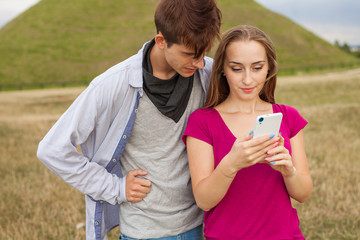 Two friends in a park with mobile phone. Summer time.