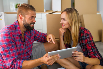 Young couple sitting on the floor with tablet pc and choosing fu