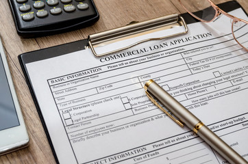 File the commercial loan application with calculator, pen on desk
